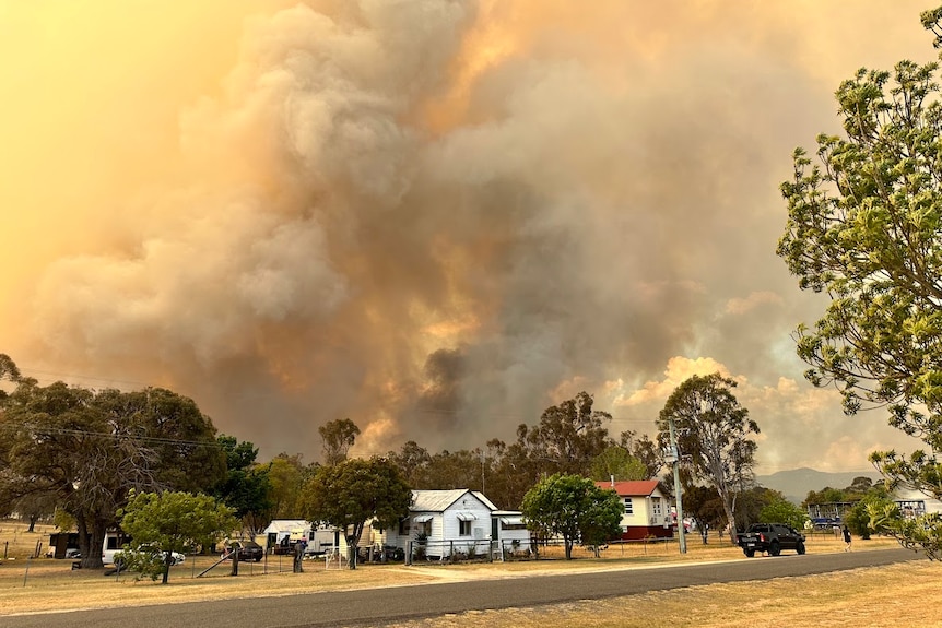 Smoke plumes behind houses and bushland