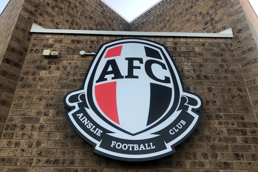 A picture of the Ainslie Football Club emblem on a brick wall