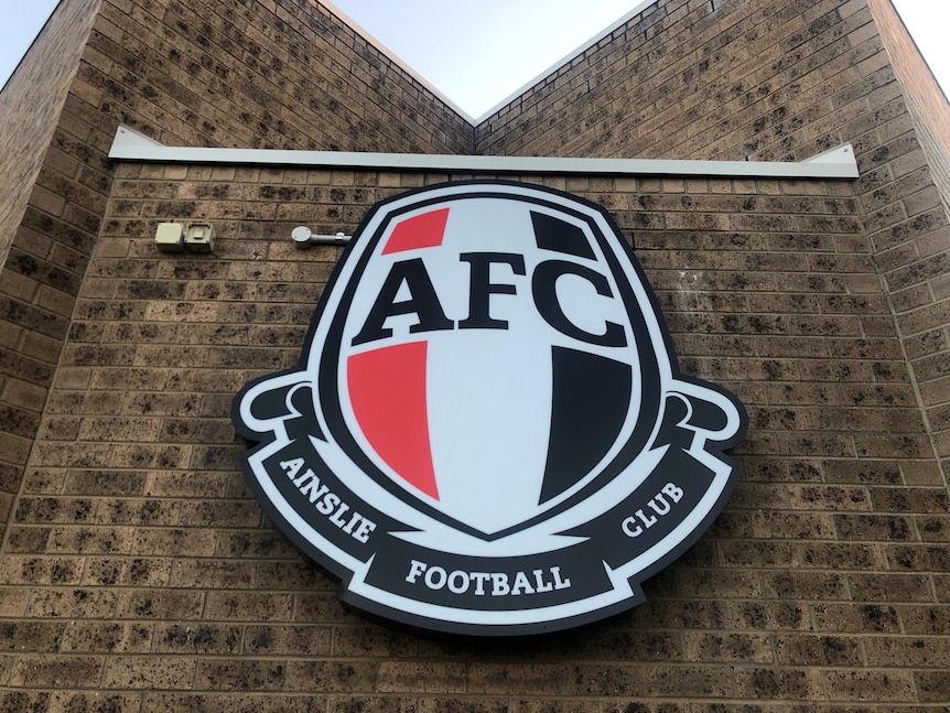 A picture of the Ainslie Football Club emblem on a brick wall