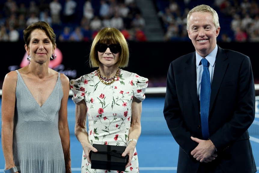 Jayne Hrdlicka, Anna Wintour and Craig Tiley standing together in a tennis stadium.