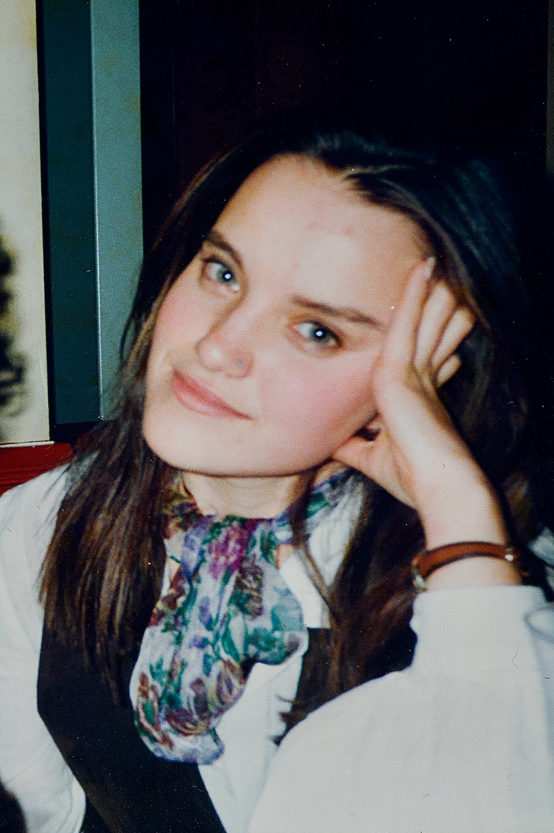 Una foto de una mujer joven mirando a la cámara con la mano en la cabeza.