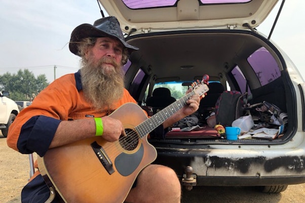 Paul Joseph strums a guitar at an evacuation story