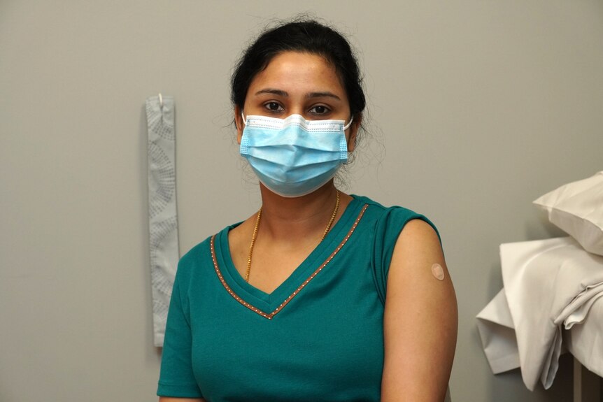 A woman wearing a face mask with one sleeve rolled up.