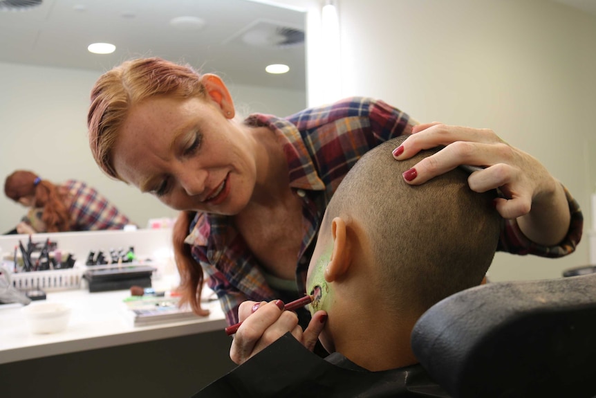 Sarah Cameron adds green face paint to her son J'Won's face