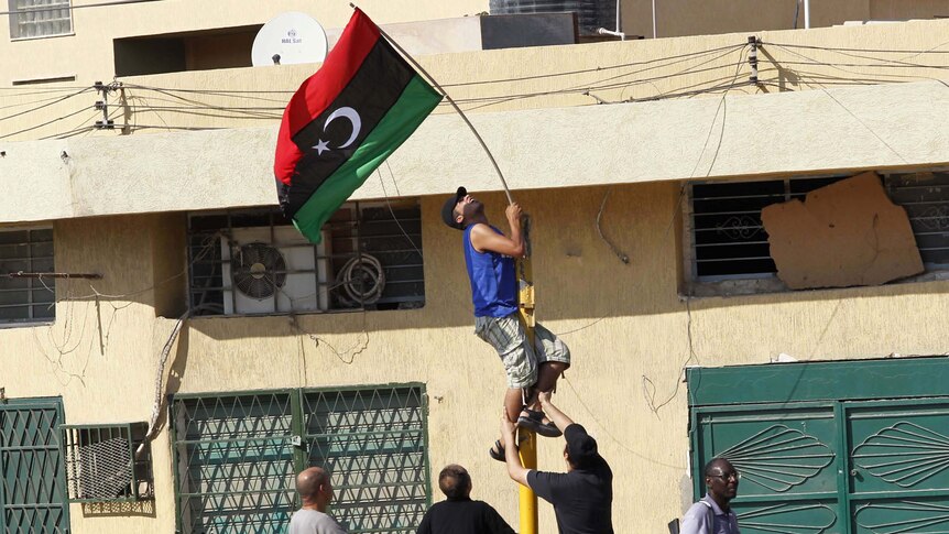 A Libyan rebel holds a Kingdom of Libya flag at Al Hadaba street, east of Tripoli.