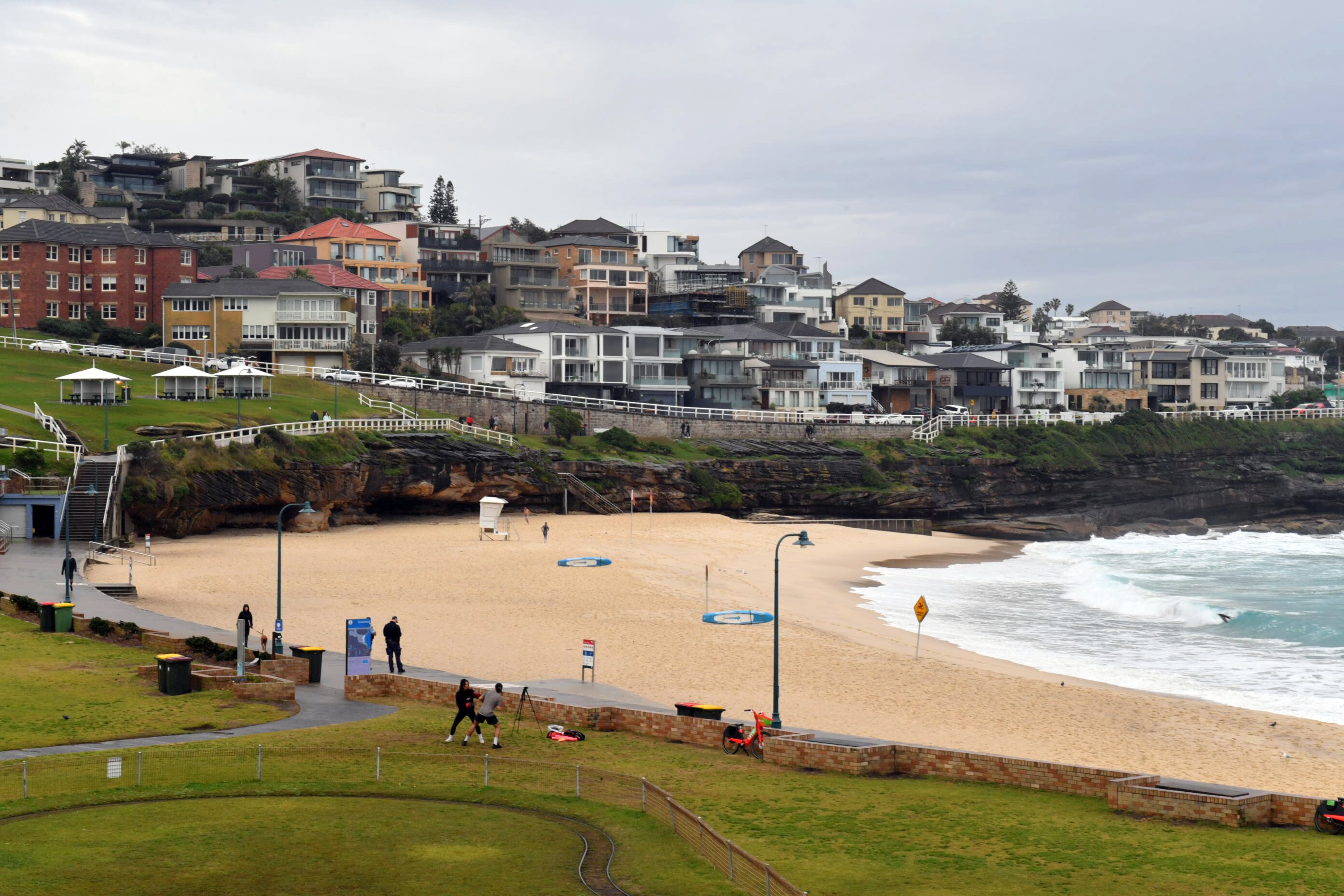 Bronte Beach, with houses on the hill, and the beach and grass area down below.