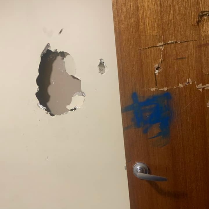 A close up photo showing damage to plaster and door