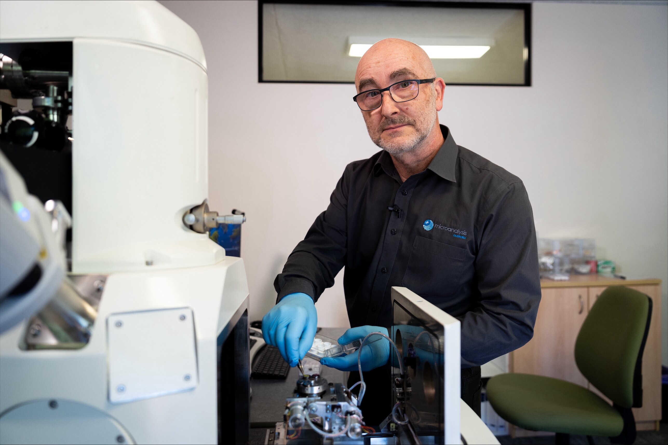 Rick Hughes usa óculos, camisa escura e luvas enquanto usa equipamentos em um laboratório de testes.