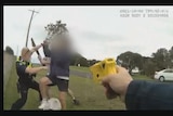 A still image from a body camera shows a police officer pointing a taser at a man attacking his colleague.