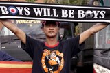 A Persija fan holds a banner reading: "Boys will be boys".