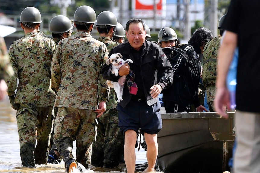 A man holding up his dog after being rescued by rescue troops in Japan.