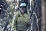 A firefighter in burnt bushland.