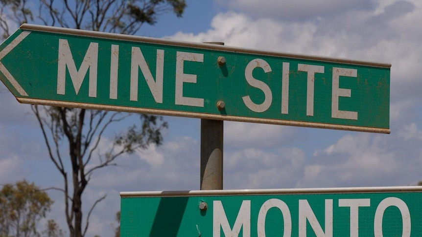 A close up image of a road sign. A green arrow points to the mine site and another points in the opposite direction to Monto.