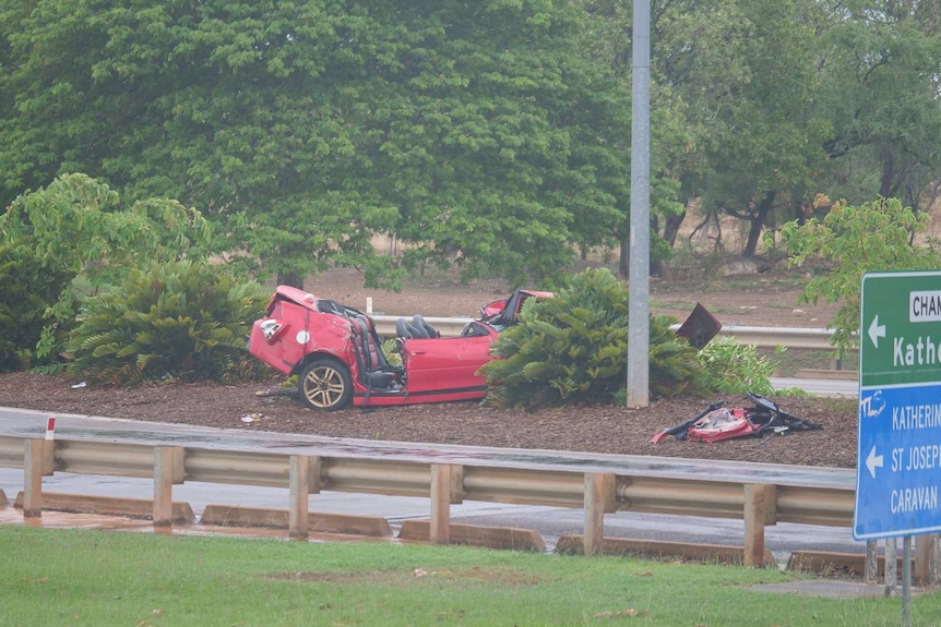 A red car is seen crashed into a median strip on the Stuart Highway.