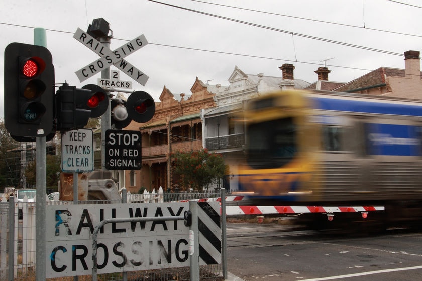 A metropolitan train passes through a level crossing.