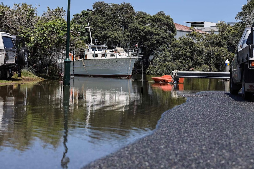 A boat near a partially flooded road at Breakfast Creek in Brisbane