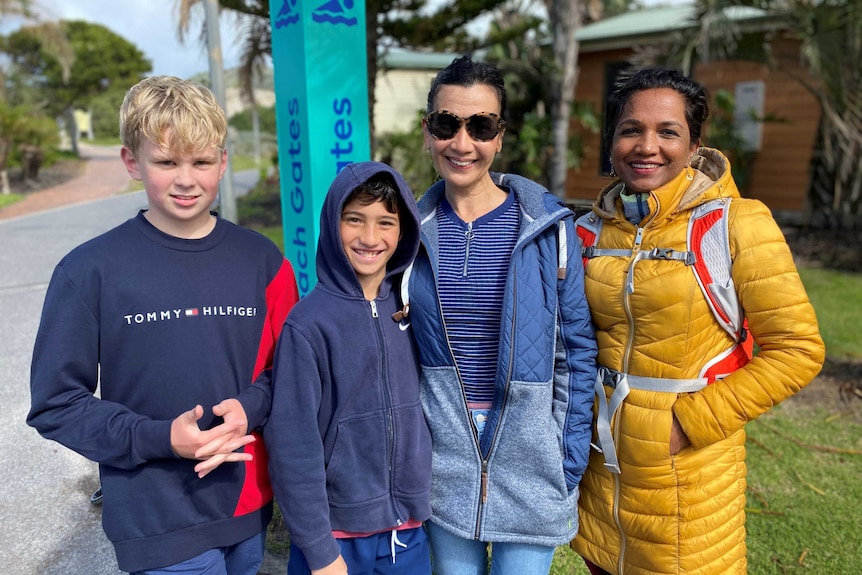 Two young boys and their mothers pose for a photo.