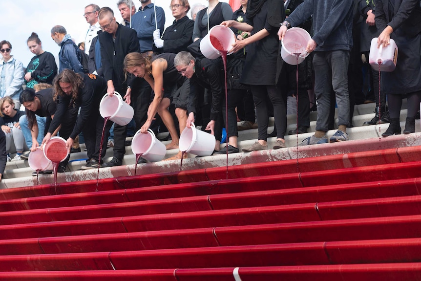 German climate inaction protesters dump buckets of red paint down stairs