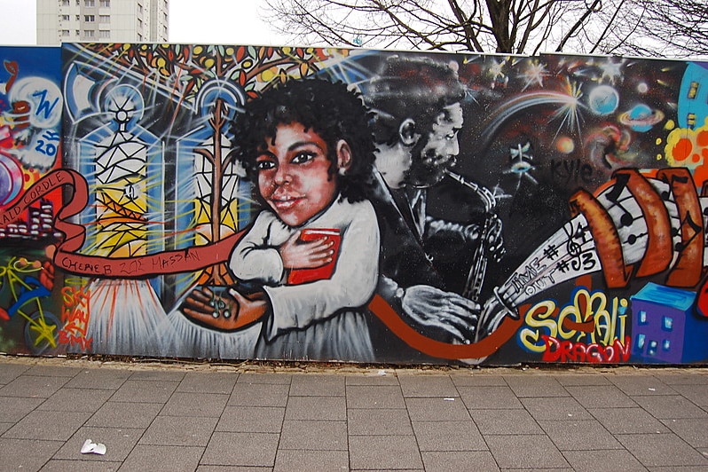 A mural with a man holding a book, and another man playing the saxophone.
