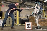 A Boston Dynamics employee pushes the new generation Atlas robot with a hockey stick.