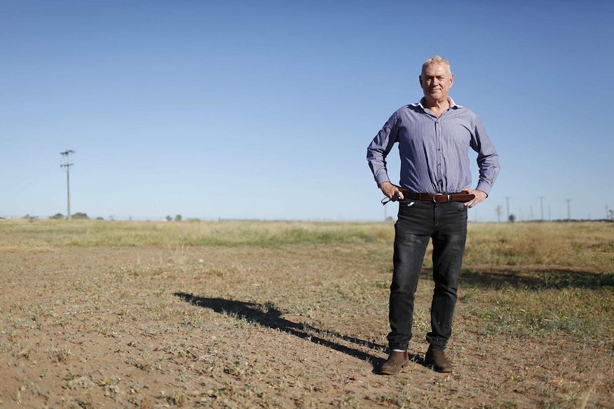 Peter Homan, from the Outback Queensland Tourism Association, stands in a field with hands on hips at Winton.