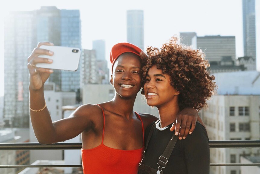 Two women smiling taking a photo on a phone together