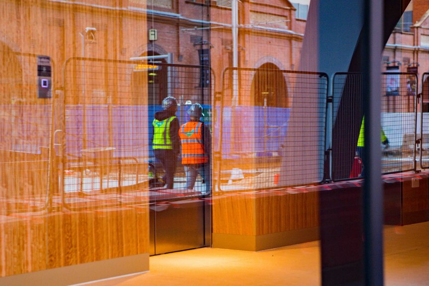 Two construction workers walking side-by-side in a city