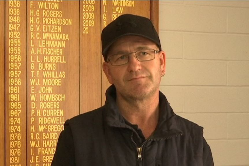 Man stands in front of board with words and names on it