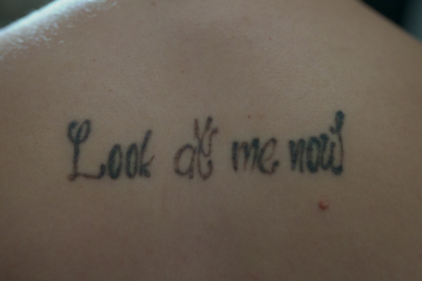 A back tattoo that reads 'look at me now'