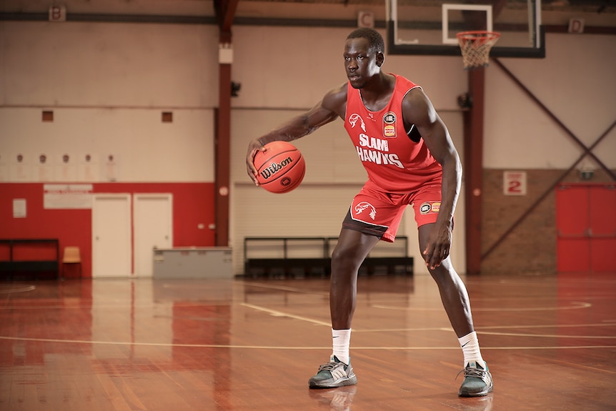 Sunday Dech dribbles the ball on an empty basketball court.