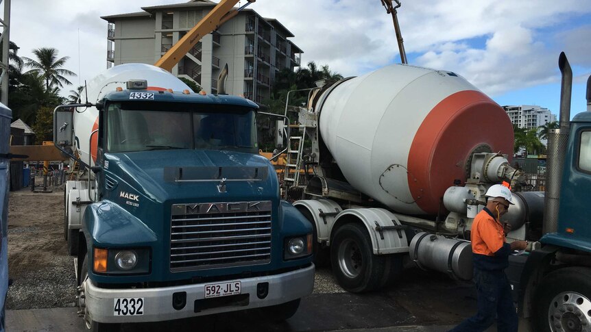 Two concrete trucks parked side-by-side wait their turn to pour concrete at the site of the Cairns Aquarium.