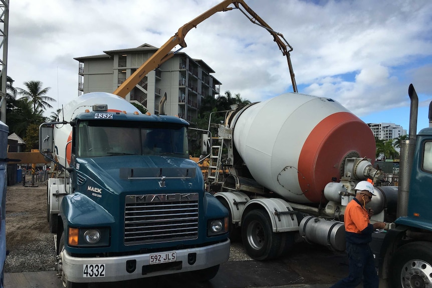 Two concrete trucks parked side-by-side wait their turn to pour concrete at the site of the Cairns Aquarium.