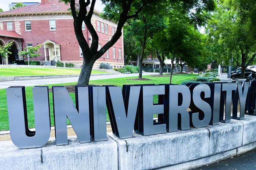 A sign spelling out university in large metal letters at an entrance to Adelaide University