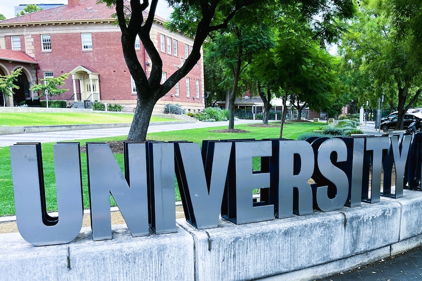 A sign spelling out university in large metal letters at an entrance to Adelaide University