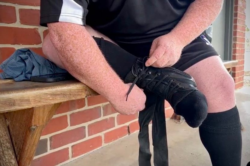 Close up shot of Huddo tying up his footy boots