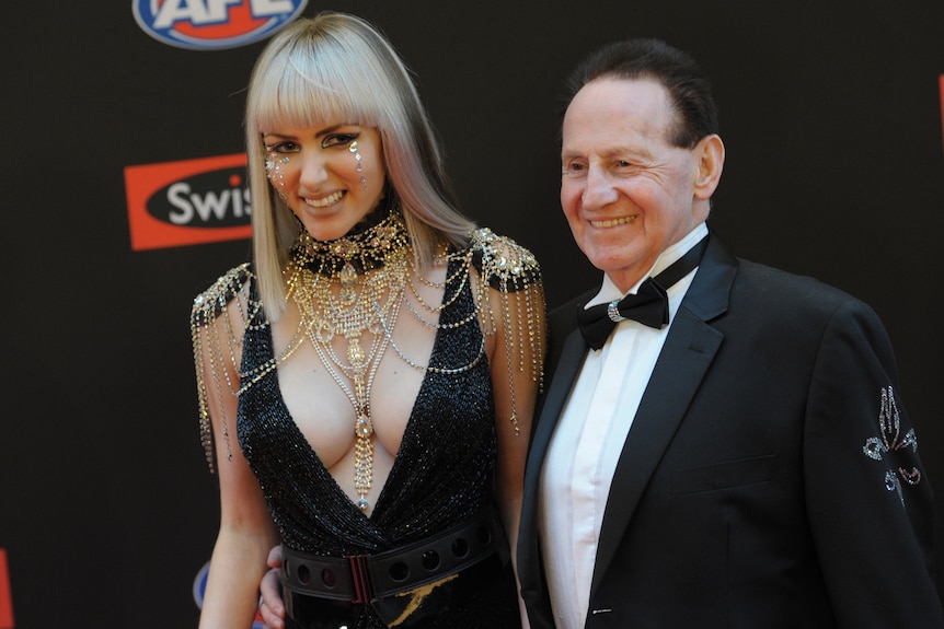 Geoffrey Edelsten smiles as he stands next to wife Gabi Grecko on the Brownlow Medal red carpet