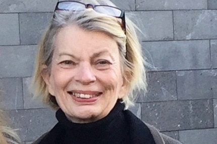 A woman wearing a black turtle neck jumper smiles at the camera