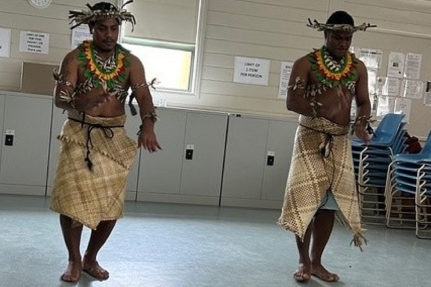 Vanuatu workers in tradtional grass skirts dancing 