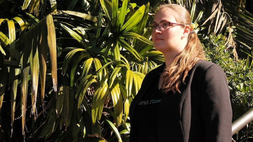 image of woman in black shiort with glasses in front of palm trees