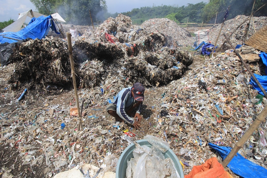 A man almost burried himself while sorting a pile of garbage.