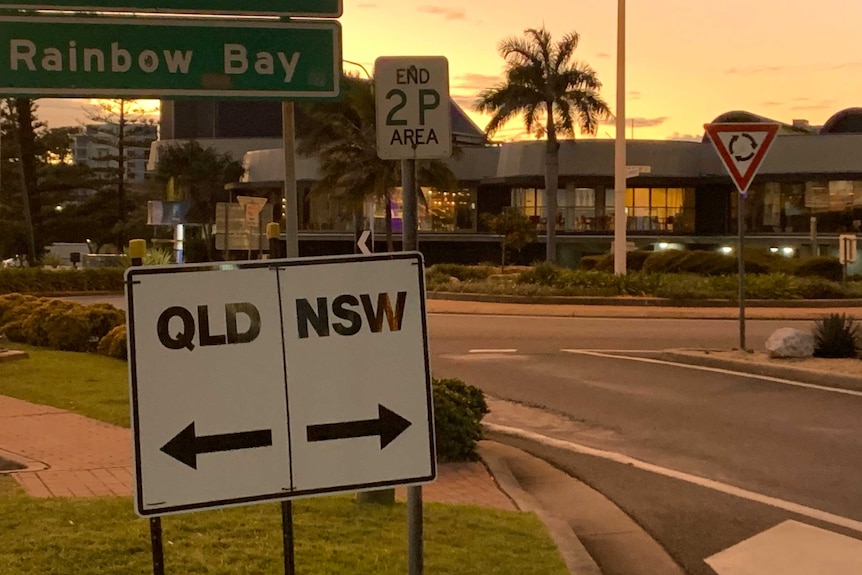 A sign with an arrow to NSW and an arrow to Qld.