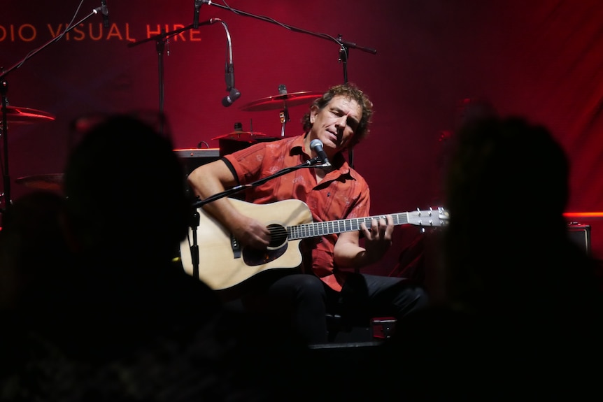 A man singing and playing guitar live