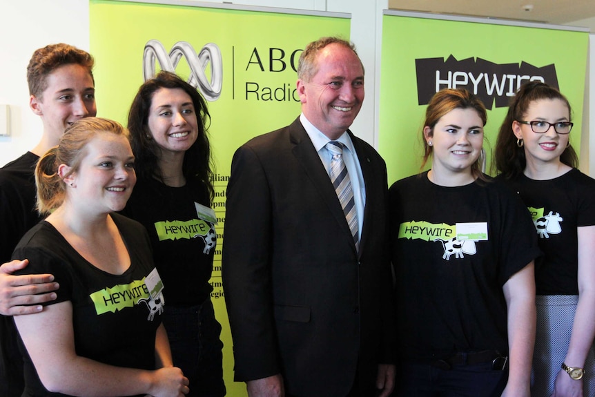 Barnaby Joyce with five young people posing for photo in front of Heywire sign.
