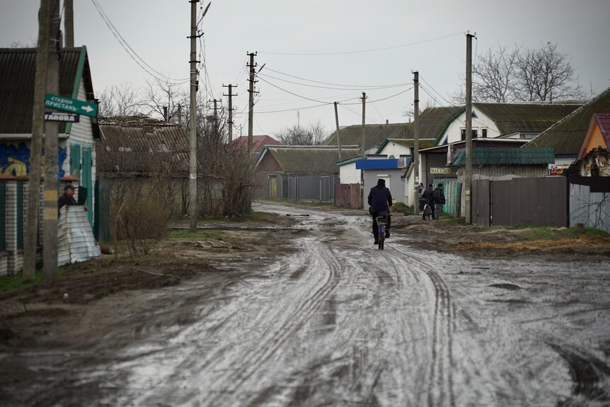 Człowiek idzie błotnistą ulicą w małym ukraińskim miasteczku.