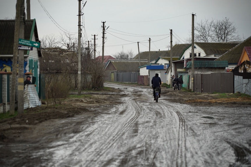O persoană merge pe o stradă plină de noroi dintr-un mic oraș ucrainean.