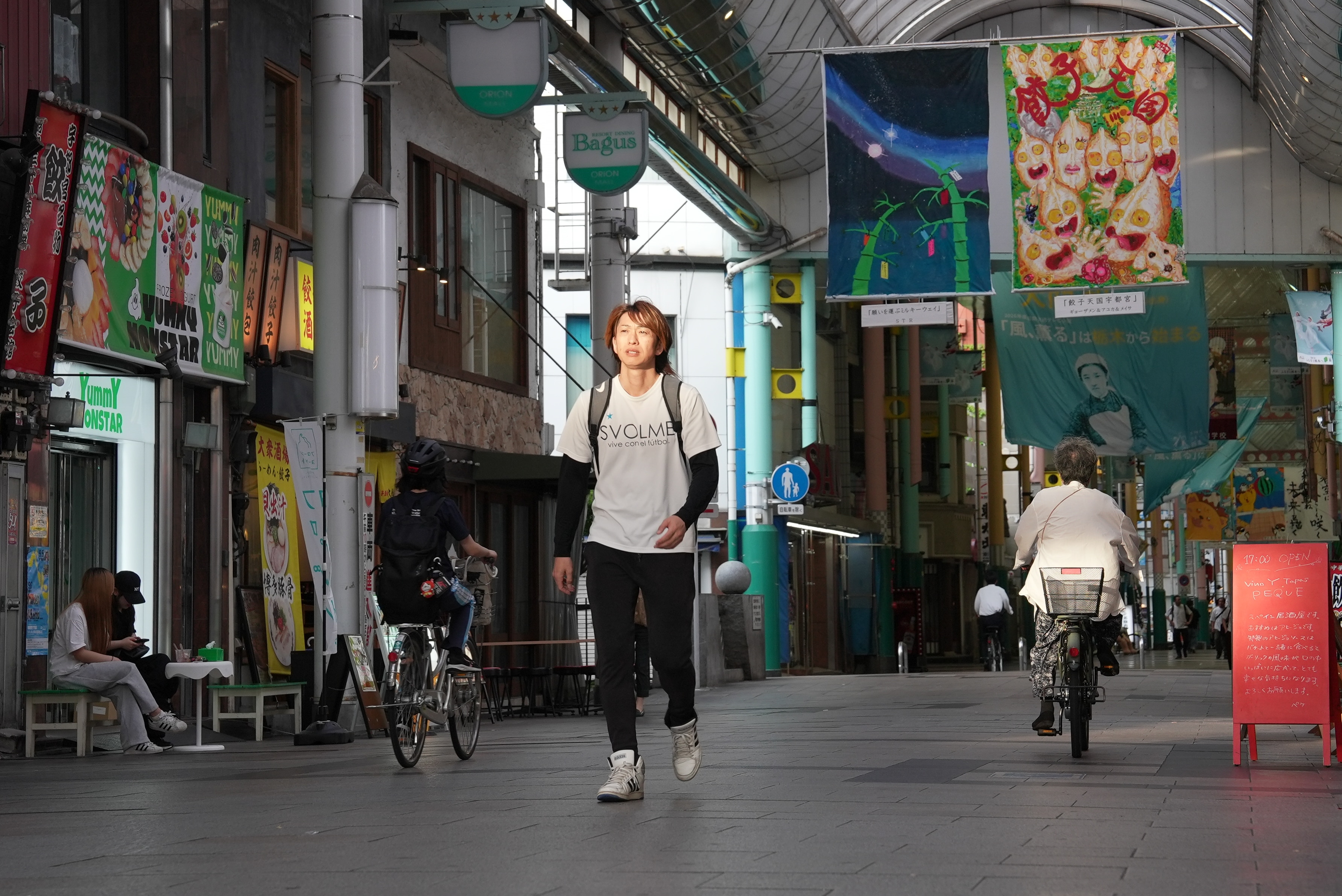 A man in a white t-shirt walks through a shopping arcade