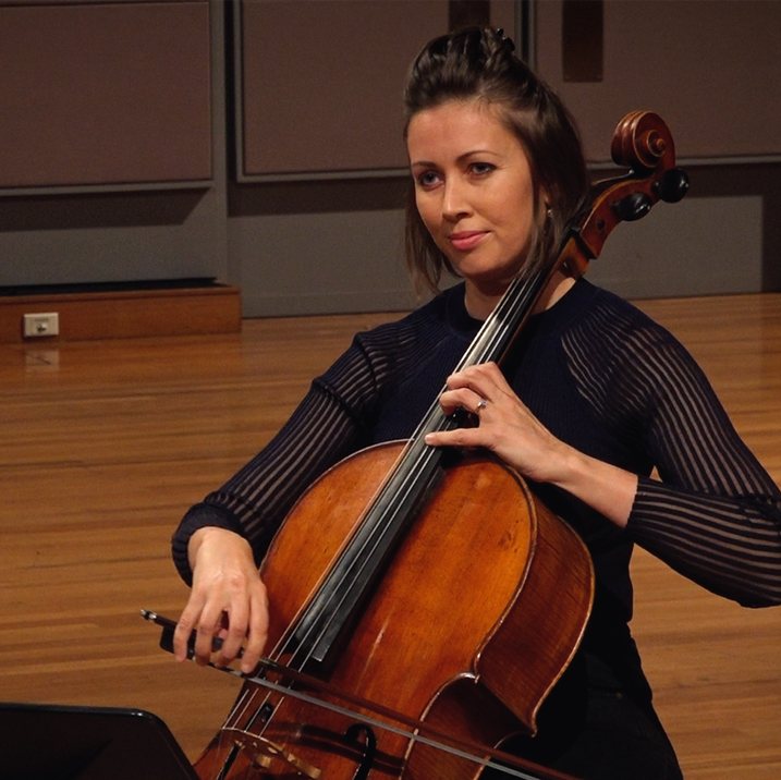 Sharon Grigoryan plays the cello in a black top with striped mesh arms.