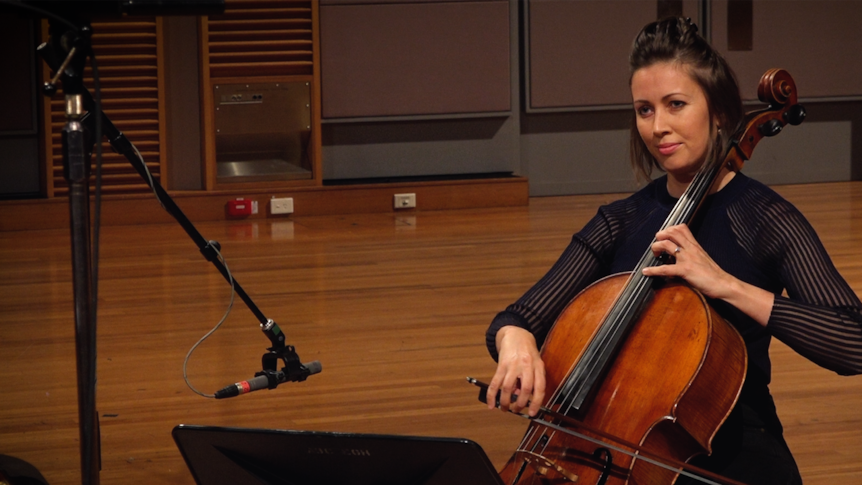 Sharon Grigoryan plays the cello in a black top with striped mesh arms.