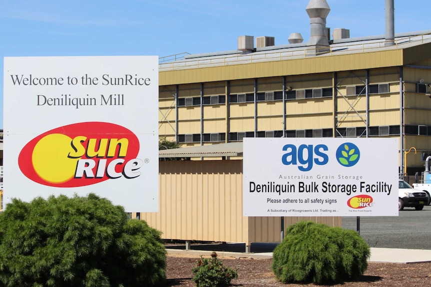 A large industrial shed with two signs in front.