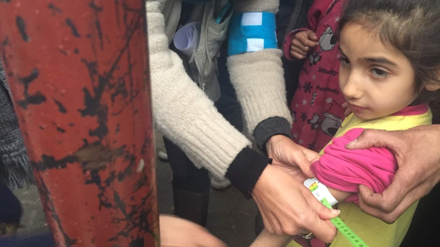 A UNICEF employee measures the arm of a malnourished child in the besieged Syrian town of Madaya